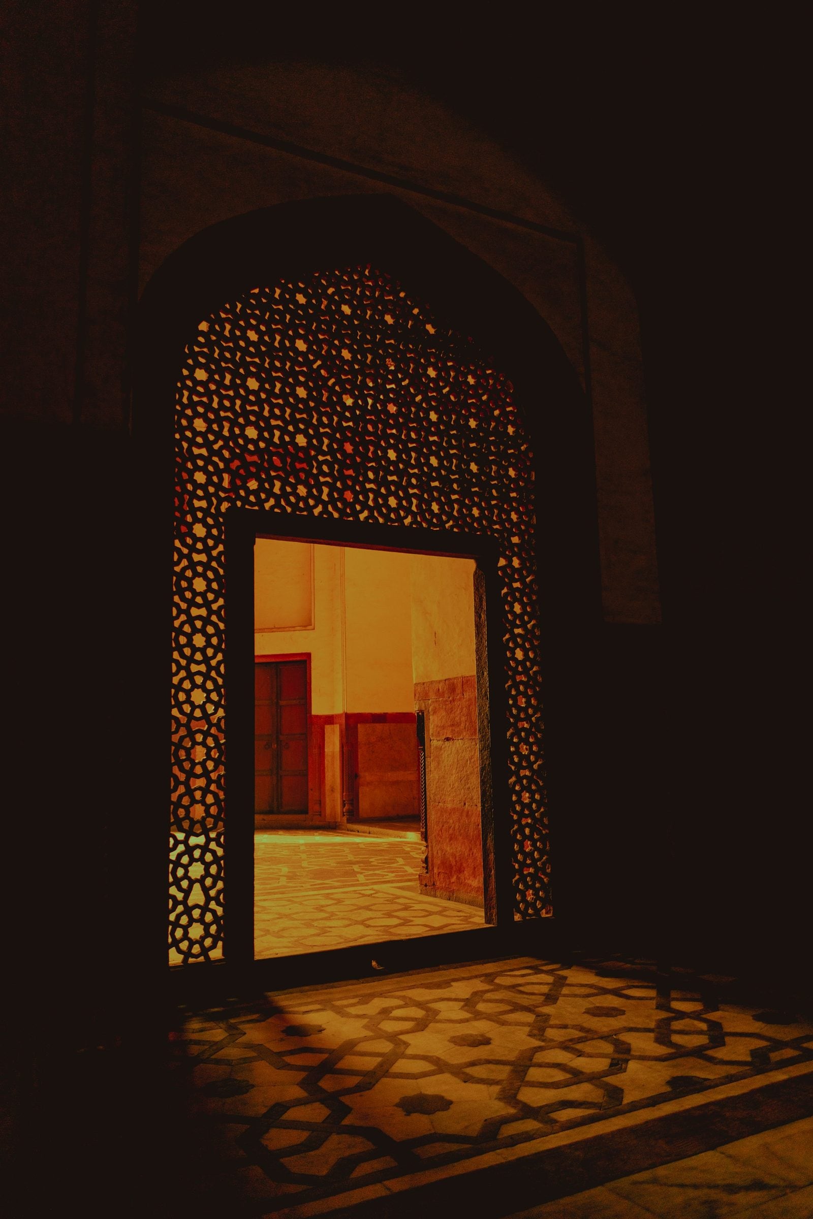 Warm light spilling through a carved doorway onto a patterned floor