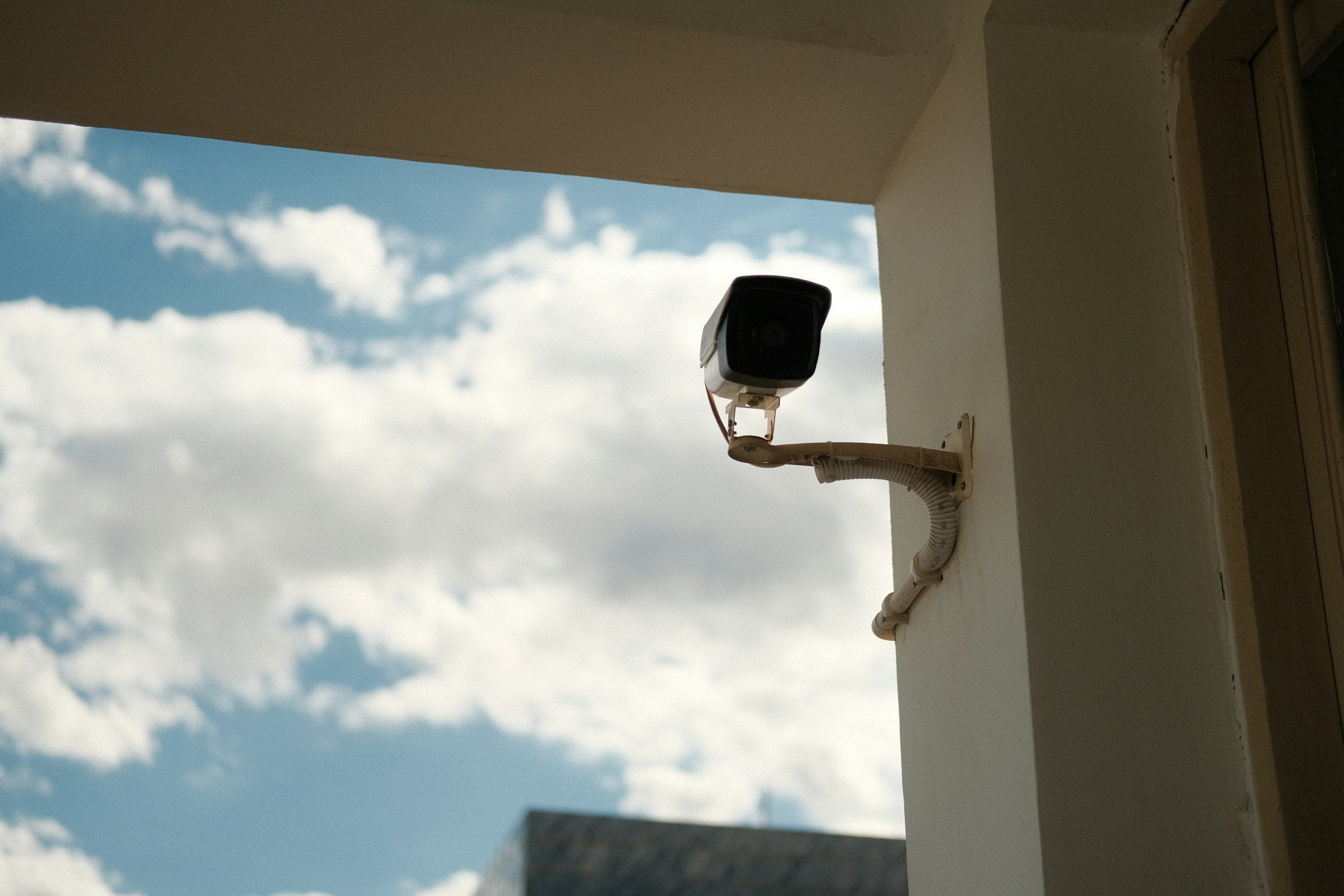 A security camera on a wall against an open sky
