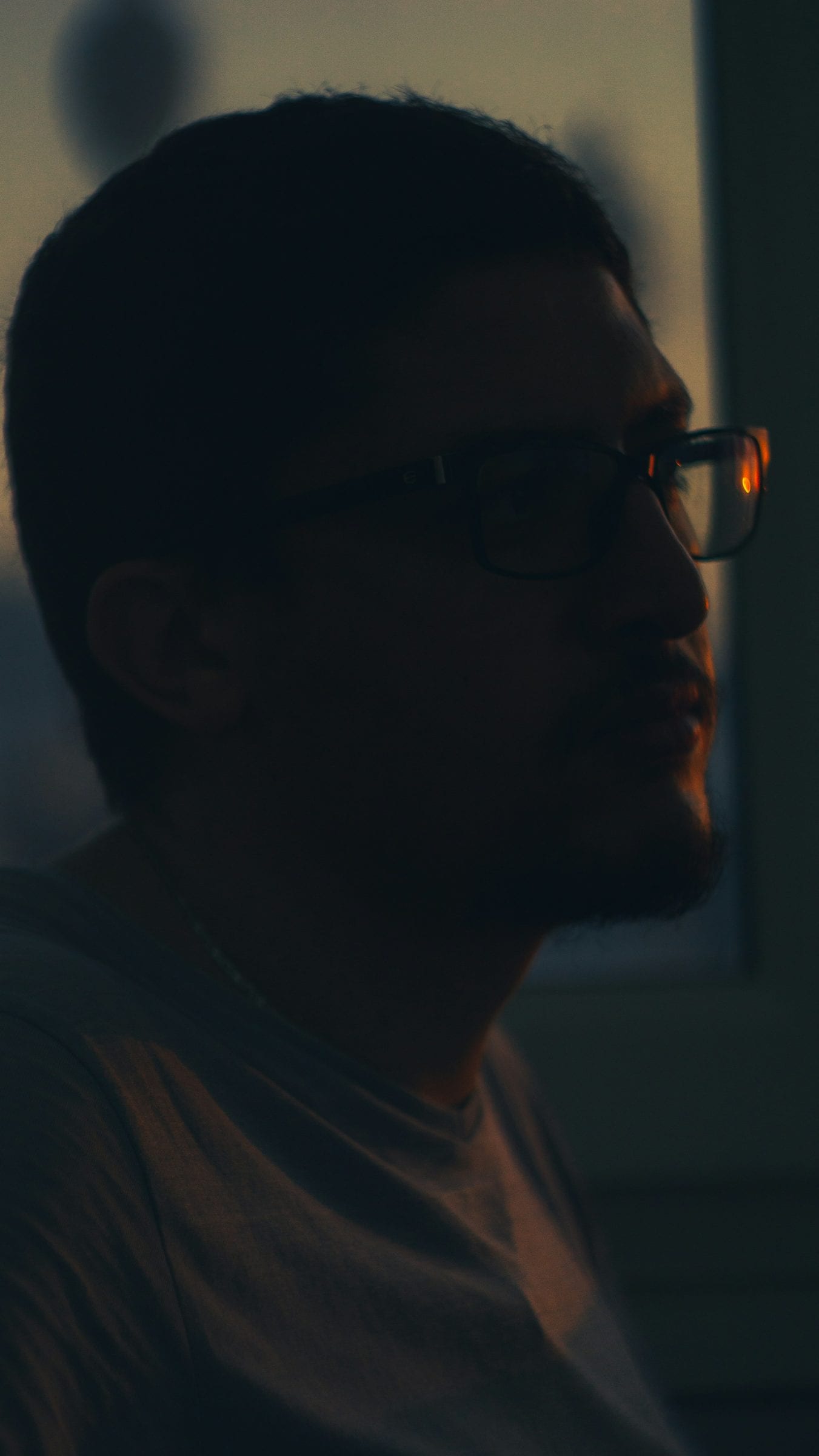 A man in profile, mostly in shadow, lit by a single window